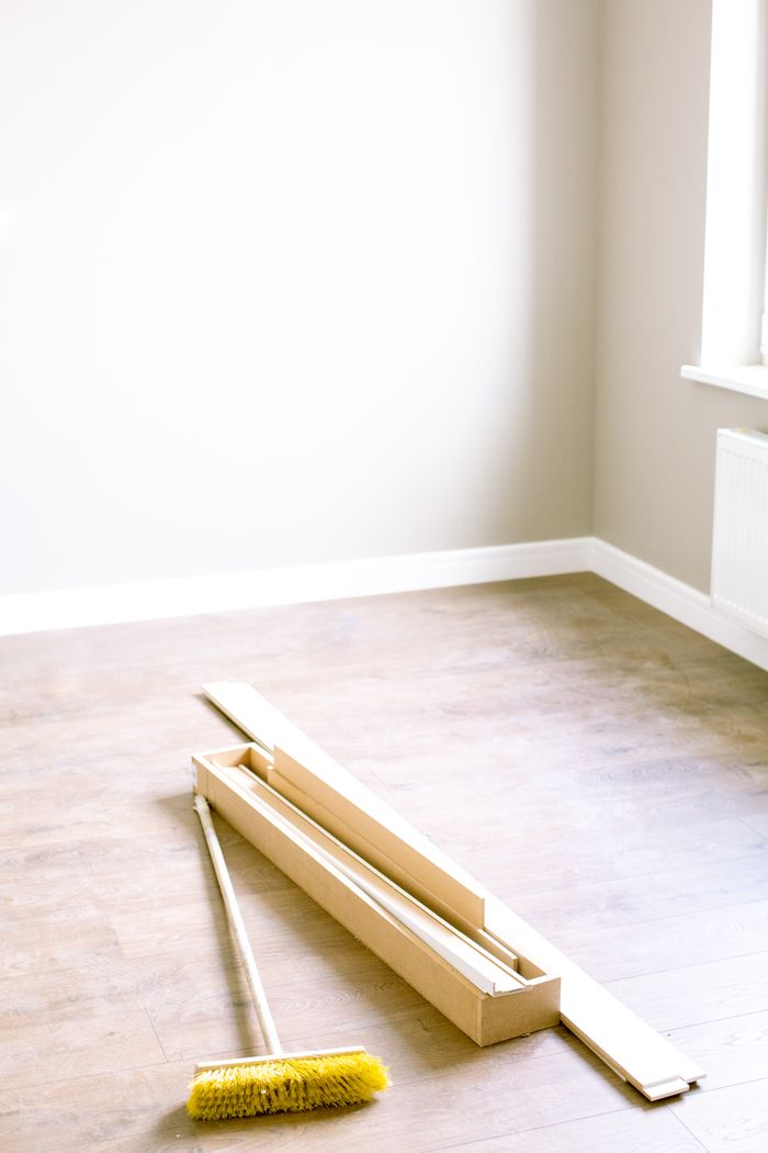 A vacant room with wooden planks and a broom, prepared for renovation.